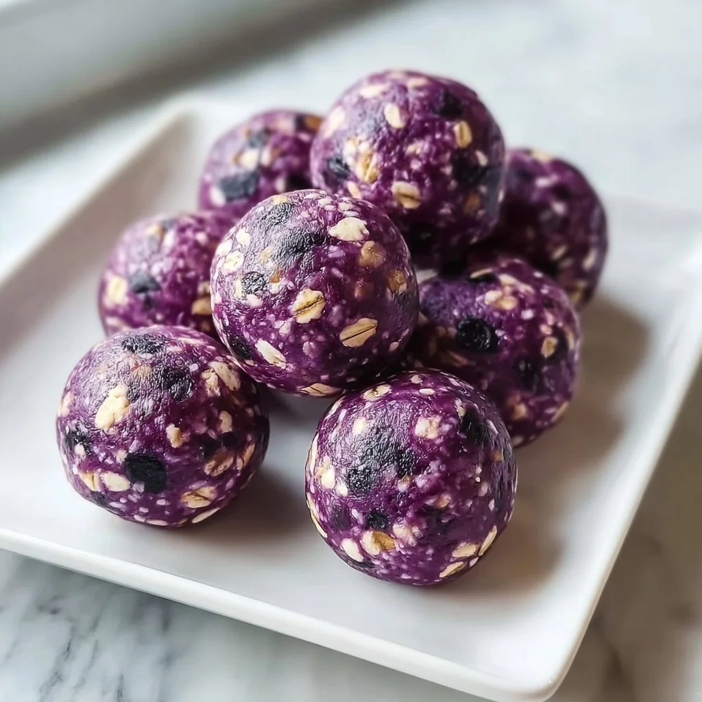 No-bake lemon blueberry protein bites on a plate with fresh blueberries.